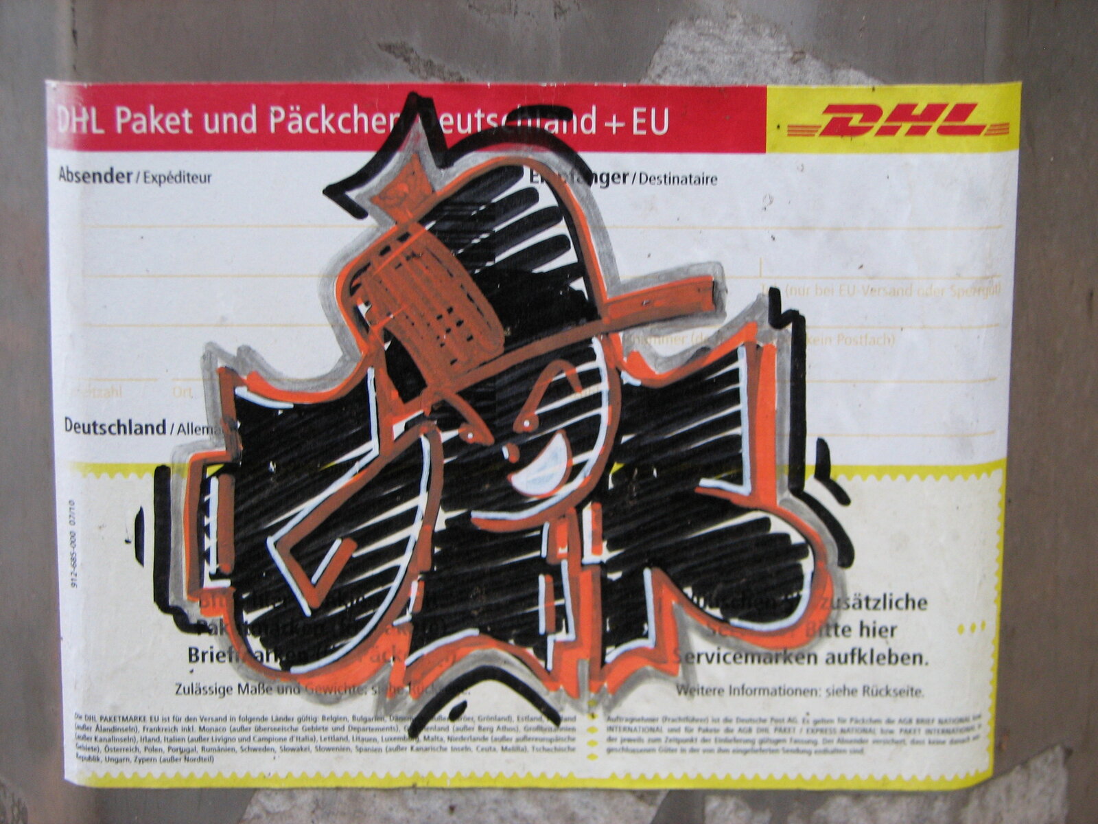 Ein aufgeklebtes Cut-out auf einem DHL-Paketaufkleber zeigt eine stilisierte orange-schwarze Figur mit ausgebreiteten Armen und Beinen in dynamischer Pose, die gleichzeitig ein Tag ist.