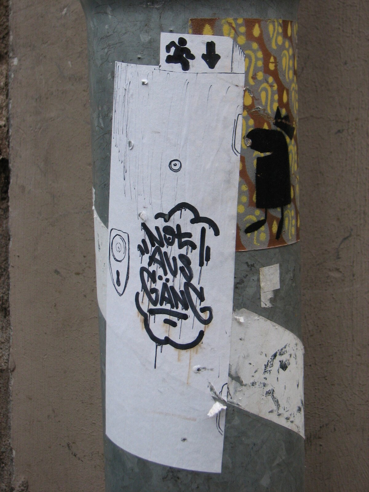 Weiße Papiersticker, auf dem ein Türschloss und ein Türspion zu sehen sind. Daneben steht mit Edding geschrieben "Notausgäng