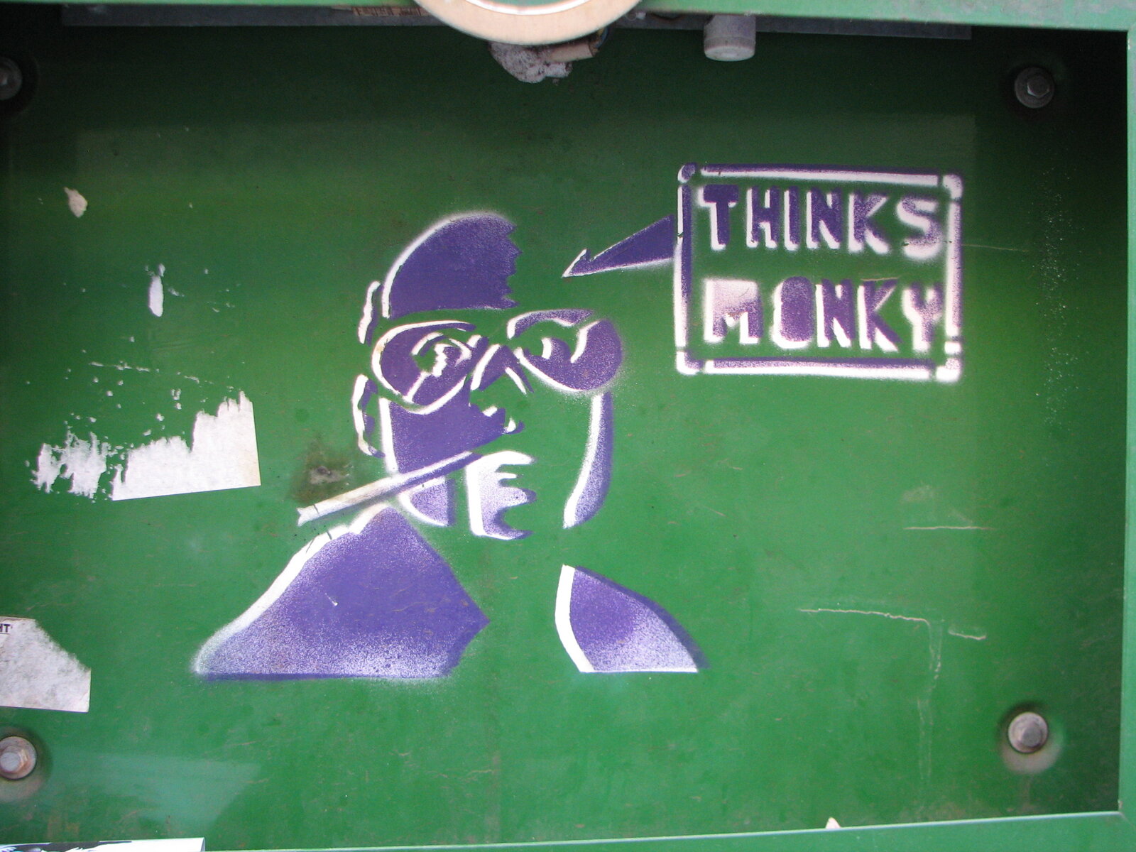 Auf grünem Untergrund eine Stencil-Figur in Violett und Weiß, die einen Charakter mit Brille zeigt. Daneben ein rechteckiger Schriftzug 'THINKS MONKY' in violetter und weißer Schrift.